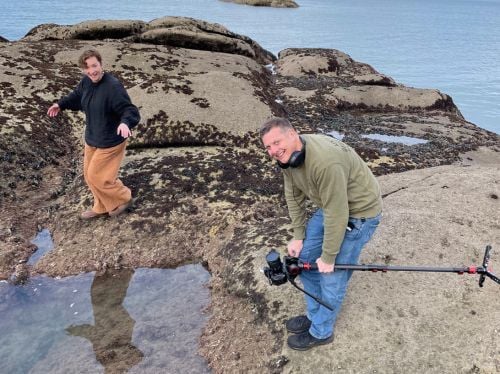 Behind the scenes - Fleur and Daniel standing on rocks next to water