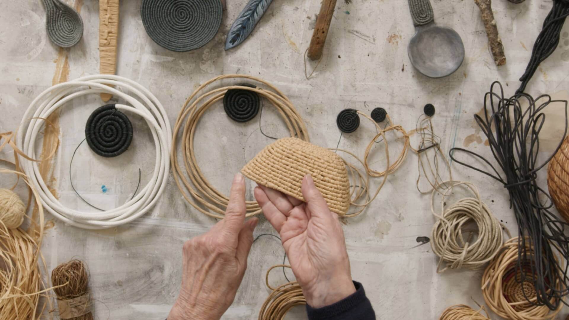 Hands making an element of basketry