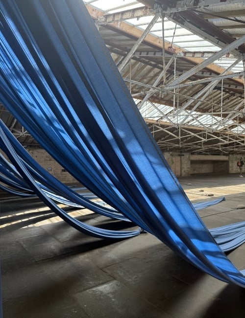 Textiles anchored by heavy stones at the Ann Hamilton exhibition