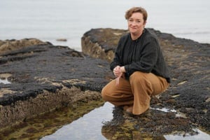 Artist Fleur Woods on rocks next to water