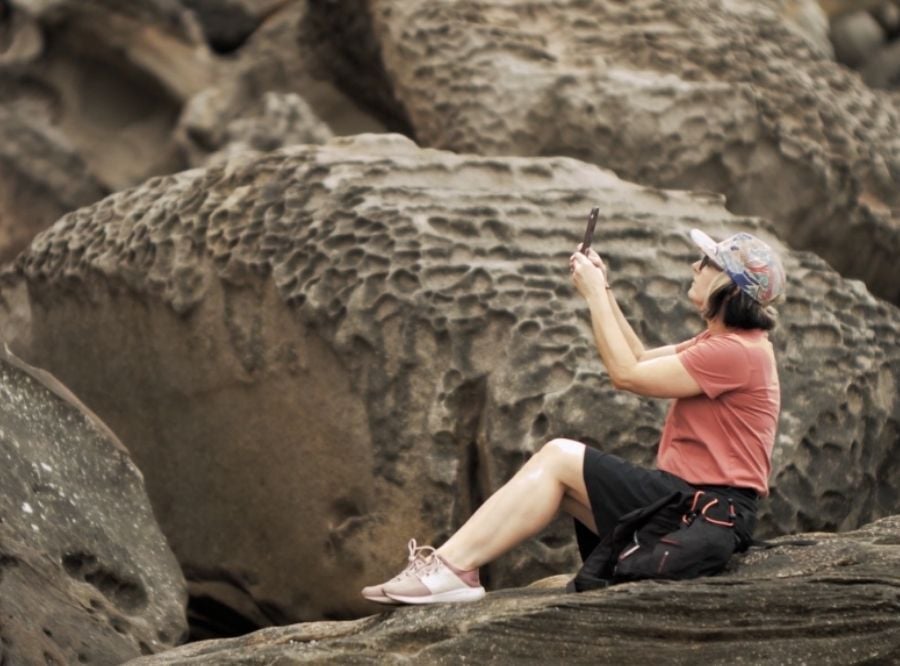 Tara sitting on rock taking photos
