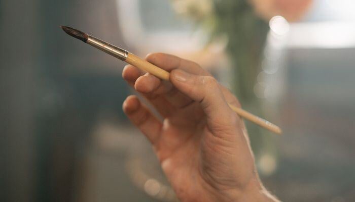 Hand holding a paintbrush