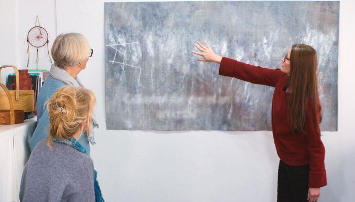 Claire Benn and two other women discussing a piece of art