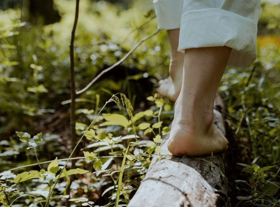 Woman's legs and feet as she walks on a log