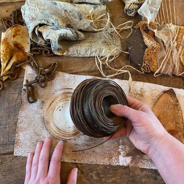 Clarissa's hand holding coiled wire while working on material