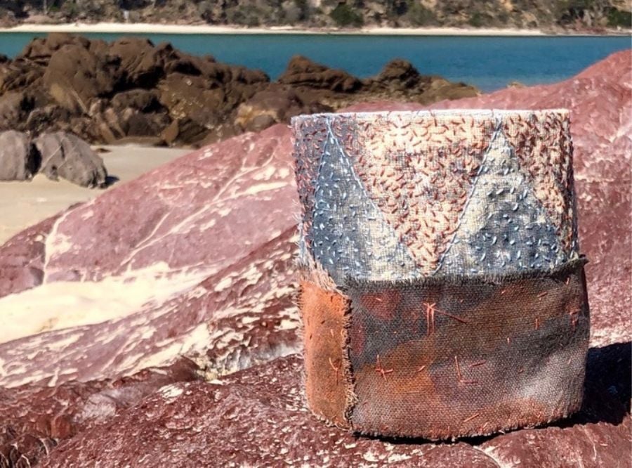 A piece of artwork by Lorna Crane placed on a rock by the water
