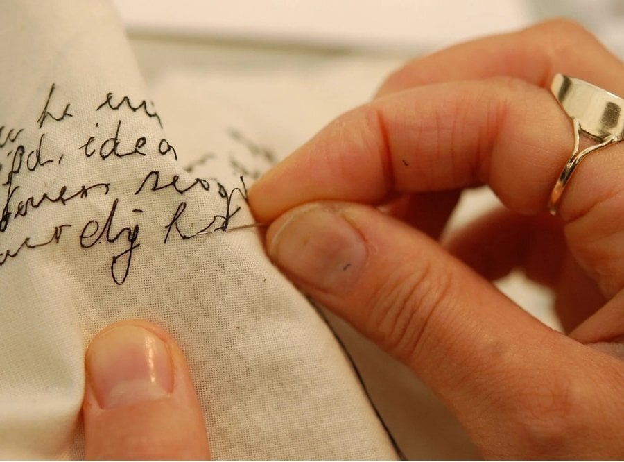 Close up of Rosalind's hand as she hand stitches embroidered lettering