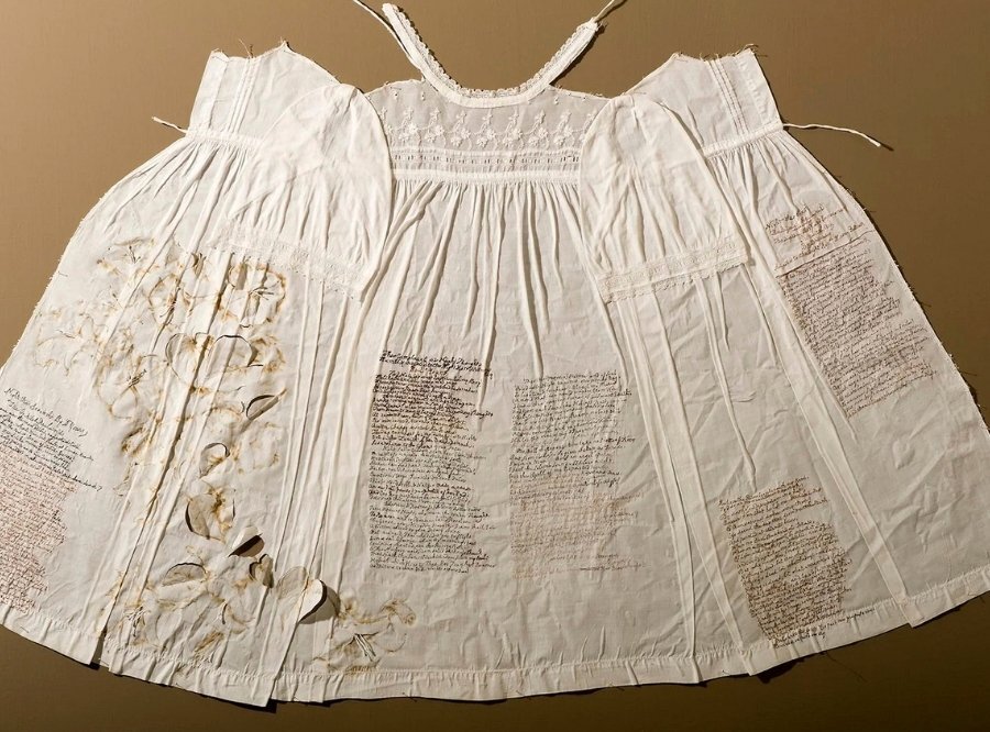 Hand-embroidered letters on a white dress - artwork by Rosalind Wyatt